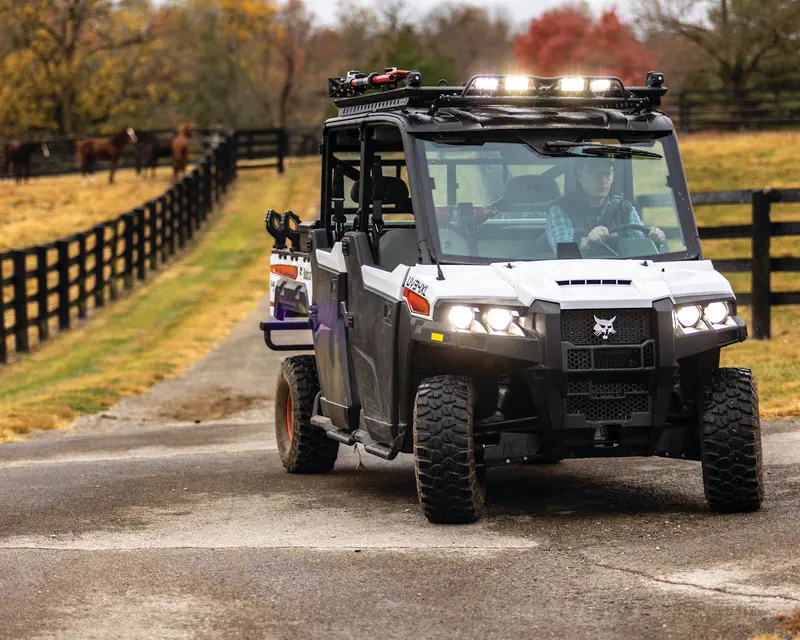 Bobcat UV34XL utility vehicle with cab and light bar on a farm road