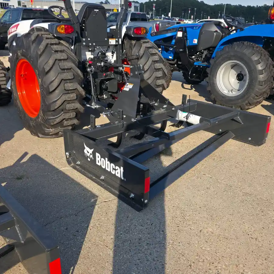 A second Bobcat box blade, Bobcat wordmark legible, hitched to a Bobcat compact tractor on the lot at Dykes Motors in Collins, Mississippi