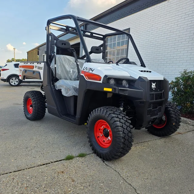 Side view of a Bobcat UV34 utility vehicle with roll cage and orange accent wheels on the lot at Dykes Motors, Collins, Mississippi