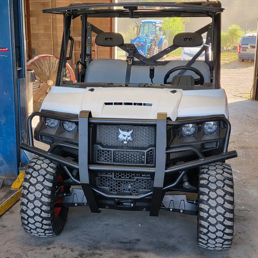 Head-on view of a Bobcat UV34 4x4 EFI utility vehicle on the shop lift at Dykes Motors, Bobcat lynx grille badge and brush guard centered