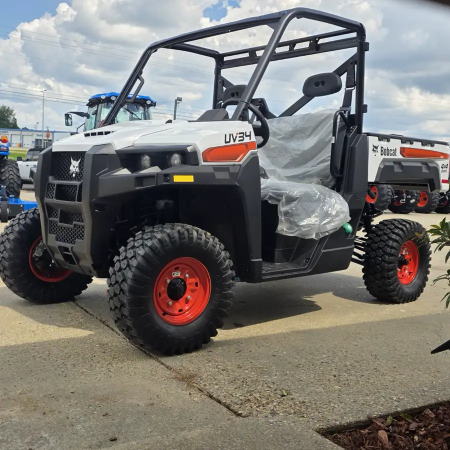 New white Bobcat UV34 4x4 diesel utility vehicle with red wheels, seats still wrapped in factory plastic, on the lot at Dykes Motors in Collins, Mississippi