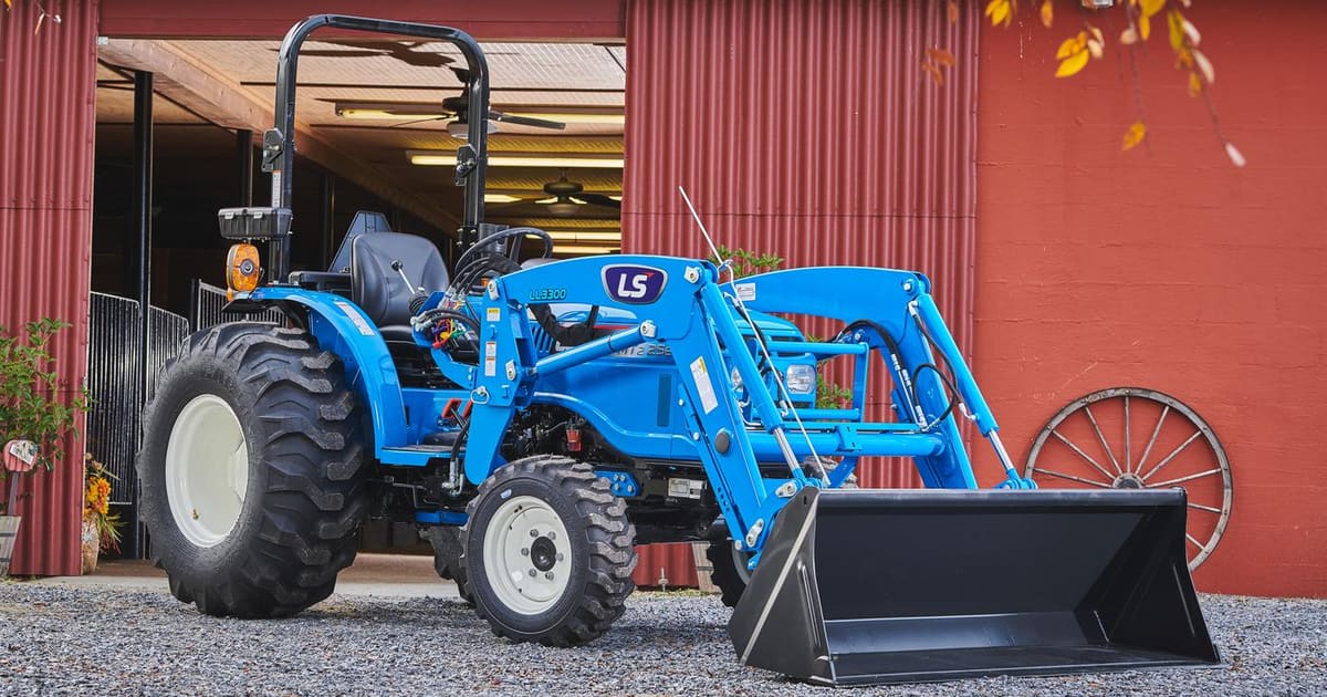 LS compact tractor with front loader outside a red barn