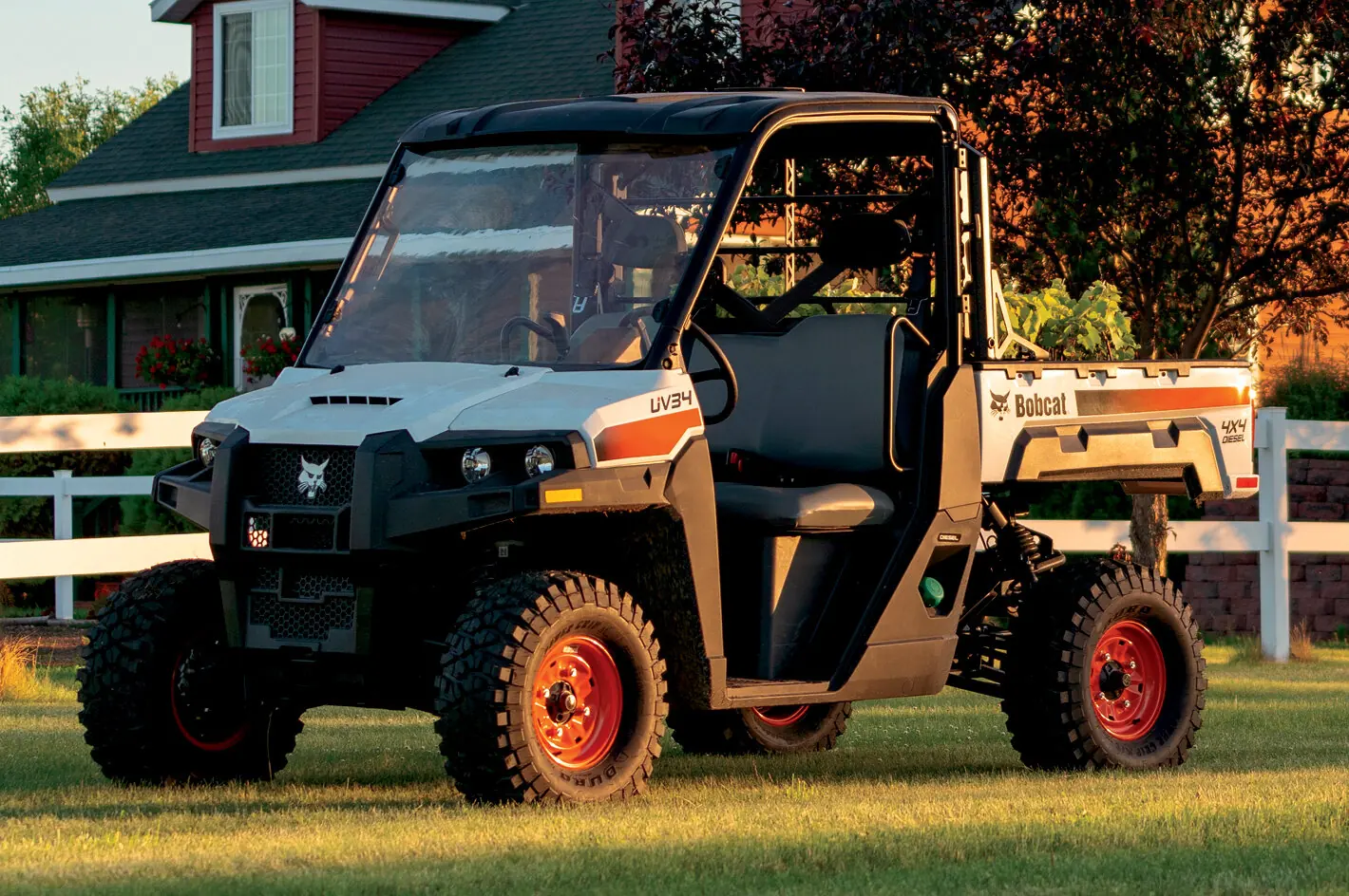 Bobcat UV34 utility vehicle on a mowed lawn by a white fence